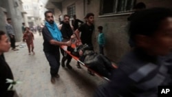 شماری از باشنده های عزه در حال اانتقال یک مجروح به شفاخانه دیده میشوند