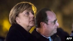 German Chancellor Angela Merkel (left) and French President Francois Hollande pay their respects to the victims of the November 13 Paris attacks on the Place de la Republic in Paris on November 25.