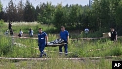 Сотрудники российских правоохранительных органов несут тело бывшего министра транспорта Романа Старовойта, который был найден мертвым от огнестрельного ранения через несколько часов после своей отставки в Одинцово под Москвой 7 июля