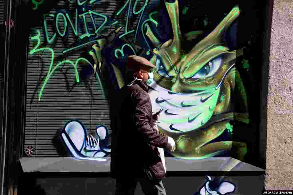 Чоловік в іспанській Саламанці проходить повз графіті, що зображає коронавірус. Весна 2020 року