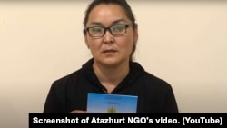 Этническая казашка из Синьцзяна Кайша Акан, незаконно пересекшая границу Казахстана, держит в руках удостоверение лица, ищущего убежище. Скриншот с видео на канале «Атажурт».