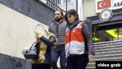 Турк полицияси бир вақтнинг ўзида 76 та манзилда рейдлар ўтказди. Суратда: полиция ходимлари рейд давомида ушланган аёллардан бирини олиб кетмоқда.