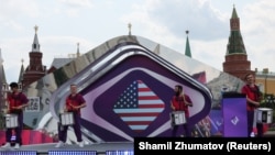 Участники выступают на фоне экрана, на котором виден флаг Соединённых Штатов Америки, во время церемонии, посвящённой обратному отсчёту 100 дней до начала конкурса песни «Интервидение». Москва, Россия, 12 июня 2025 года