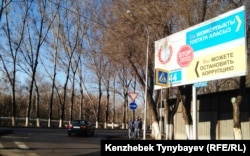 Жемқорлықпен күресуге шақырған жарнама жанында тұрған ішкі істер әскери қызметкерлері. Алматы. 2015 жыл.