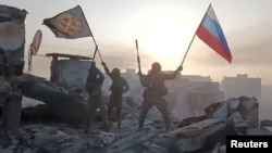 Wagner mercenaries wave flags of Russia and the Wagner Group atop a building in an unidentified location in this still image obtained from a video released on May 20. 