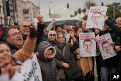 Люди скандируют лозунги и держат плакаты с изображением мэра Стамбула Экрема Имамоглу во время протеста возле департамента безопасности Vatan, куда должны были доставить Имамоглу после ареста в Стамбуле, 19 марта 2025 года