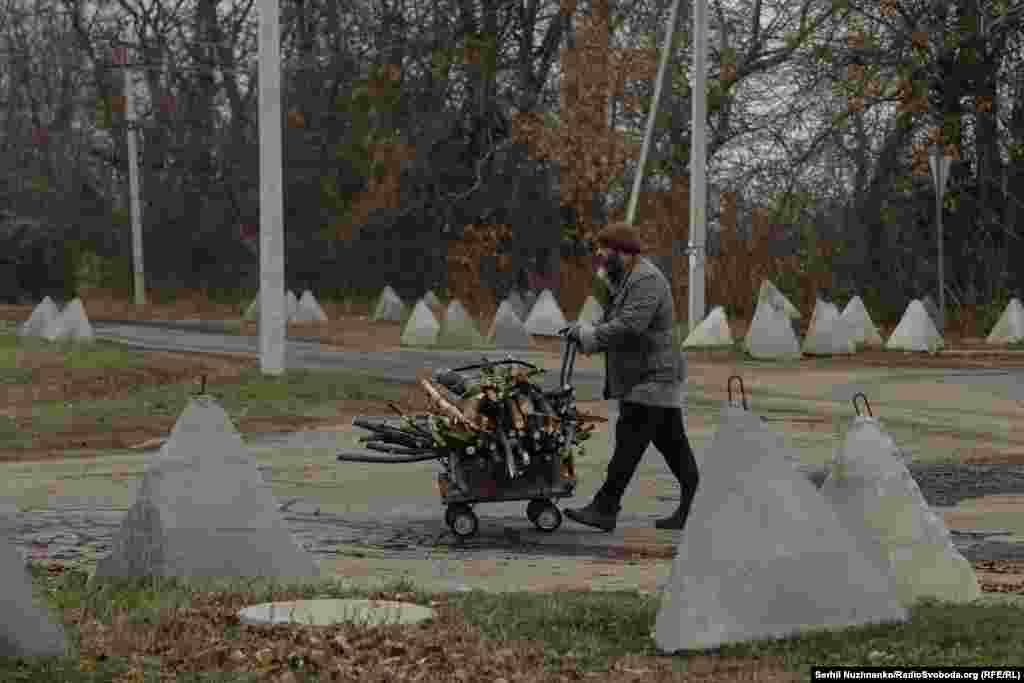 Мужчина с тележкой дрова. За ним &mdash; дорога в сторону Шевченко, куда тоже продвигаются российские войска. Некоторые мирные жители, с которыми мы говорили, рассказали нам о друзьях и соседях, которые возвращаются в Покровск, несмотря на шаткое положение города. Они вернулись, потому что не смогли найти работу в другом месте и остались без денег; кто-то не смог привыкнуть к жизни вдали от родного города. Многие говорят, что единственная помощь от государства для официально зарегистрированных беженцев &mdash; это выплата в размере 11 тысяч гривен (265 долларов США), а те, кто уезжает самостоятельно, не могут рассчитывать даже на эту сумму