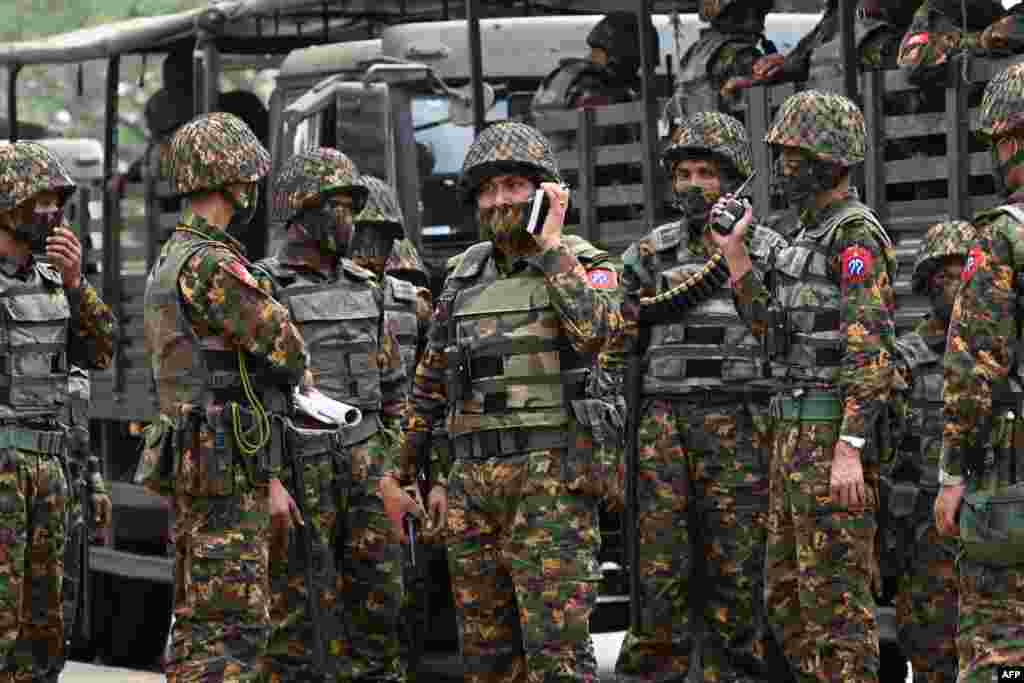 Аскердик төңкөрүшкө каршы нааразылык чарага чогулган калайыкка каршы туруу үчүн жоокерлер Борбордук банктын алдында турушат. Янгон шаары, Бирма. 2021-жылдын 15-февралы.