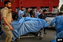 Парамэдыкі і супрацоўнікі паліцыі нясуць турыста, параненага падчас нападу ў Кашміры 22 красавіка 2025 году