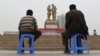 China - TO GO WITH CHINA-XINJIANG-UNREST-MIGRATION-POPULATION BY BENJAMIN HAAS   This photo taken on April 16, 2015 shows a Uighur man and boy watching a performance under a statue of late communist leader Mao Zedong meeting with a Uighur, in the central 