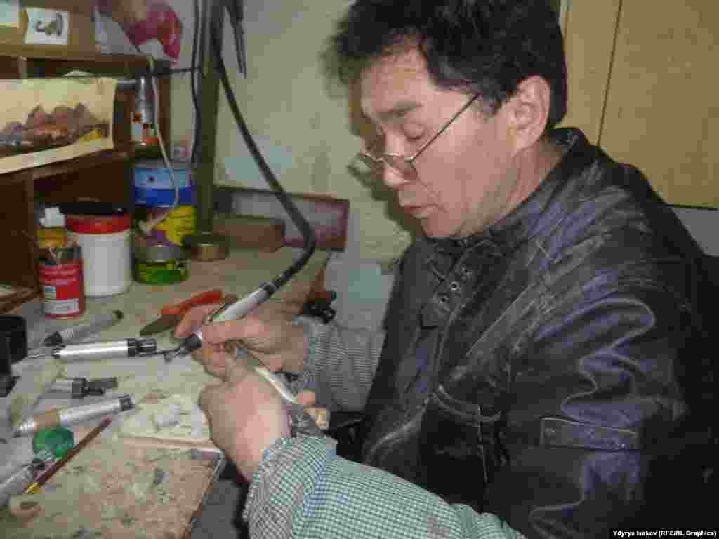 Асан Турсунмаматов мүйүз кынга сөөктү чаптап, сөөккө болсо Сулайман-Тоонун көрүнүшүн чегерүүдө.