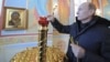 Премьер-министр России Владимир Путин зажигает свечу в часовне во время визита в Хакасию. 19 декабря 2011 года. 