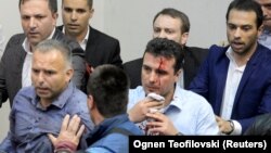 Injured Social Democrat leader Zoran Zaev is escorted out of the parliament in Skopje on April 27.