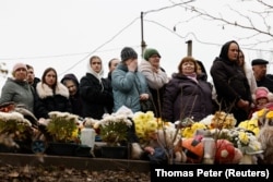 Местные жители наблюдают, как спасатели извлекают тела погибших в результате попадания российской ракеты в жилой дом в Тернополе, 21 ноября 2025 года