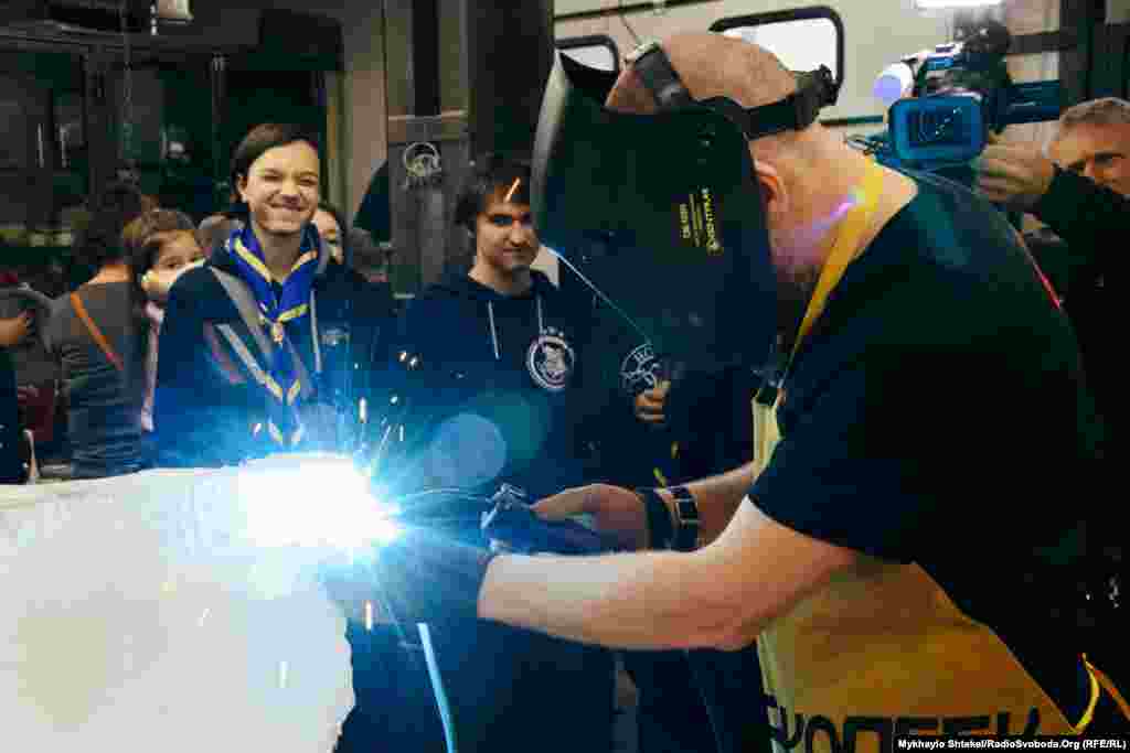 Максименко приварює монети одна за одною і водночас пояснює, що майбутні сотні тисяч монет будуть кріпитися до силового сталевого каркасу