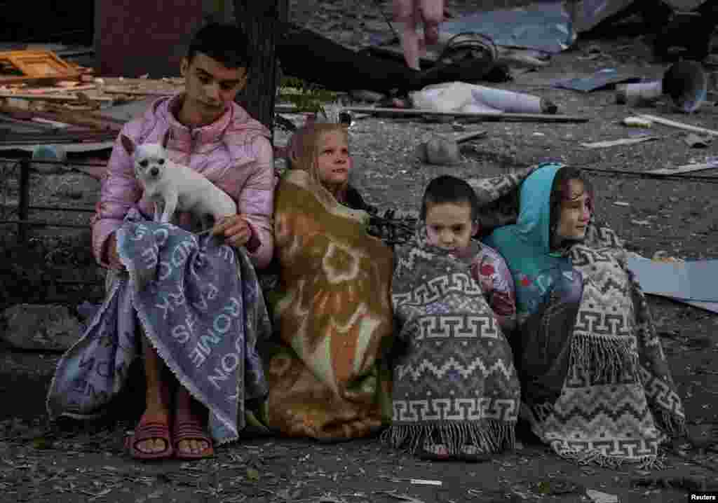 Жители сидят на месте жилого дома, пострадавшего от ударов российских беспилотников и ракет, Киев, Украина, 28 августа 2025 года. REUTERS/Stringer