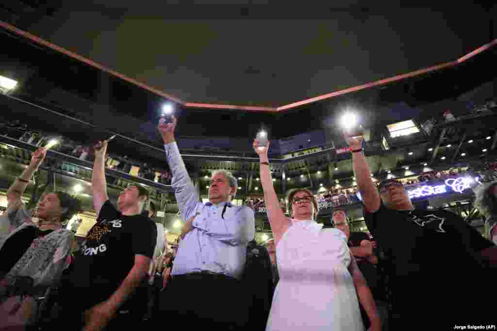 Люди поднимают вверх смартфоны во время зачитывания имен жертв массовой стрельбы 14 августа 2019 года в университете Southwest University Park в Эль-Пасо, штат Техас.