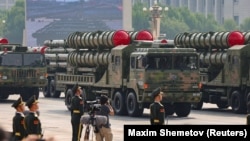 Members of the People's Liberation Army stand as the HQ-22A missile defense systems pass by during the September 3 military parade.
