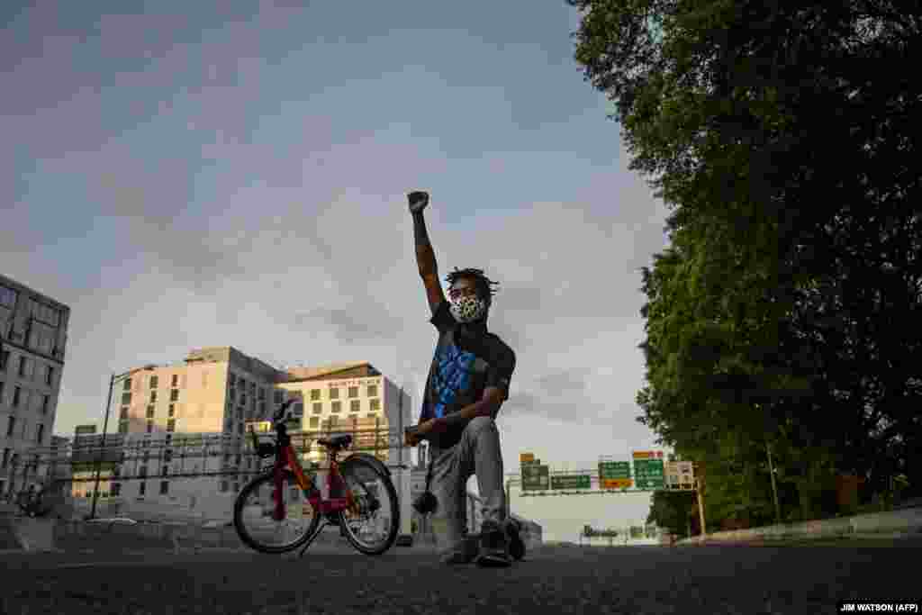 Протестувальник стає на коліно та піднімає кулак під час протесту проти загибелі Джорджа Флойда, перекривши рух на трасі І-395 у Вашингтоні, округ Колумбія, США