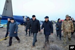 Члены госкомиссии по расследованию и местные чиновники проходят мимо обломков Embraer 190 авиакомпании Azerbaijan Airlines. 26 октября 2024 года