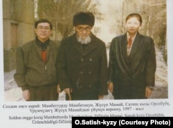 Кытайлык кыргыздардын залкар манасчысы Жусуп Мамай кыргызстандык Орозбүбү Сатиш кызы жана артыштык илимпоз Мамбеттурду Мамбетакун (сол жакта) менен. Үрүмчү шаары, 1997-жылдын ноябры.