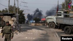 Бойовик угруповання «ДНР» на фоні диму, який піднімається над Донецьким аеропортом після обстрілу, 23 вересня 2014 року