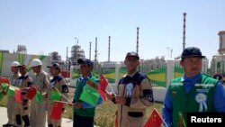 Рабочие держат государственные флаги Китая и Туркменистана на церемонии запуска инфраструктуры на газовом месторождении Галкыныш, Туркменистан, 4 сентября 2013 г.
