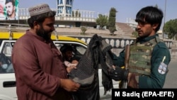 Kandagar. Owgan howpsuzlyk işgäri barlag nokadyna gelen geçegçini barlaýar. 12-nji awgust, 2021.
