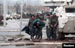 Жителі Сараєва ховаються за БТРом миротворців ООН від снайперського вогню під час облоги міста військами боснійських сербів. Фото 1993 року