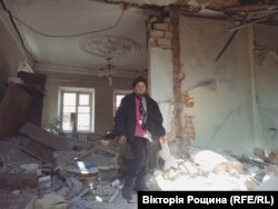 Мешканка Маріуполя Надія на фоні знищеного снарядом будинку. Жінка тікала з міста з початком обстрілів, а наразі повернулась подивитися на руїни та забрати речі. Квітень 2022 року