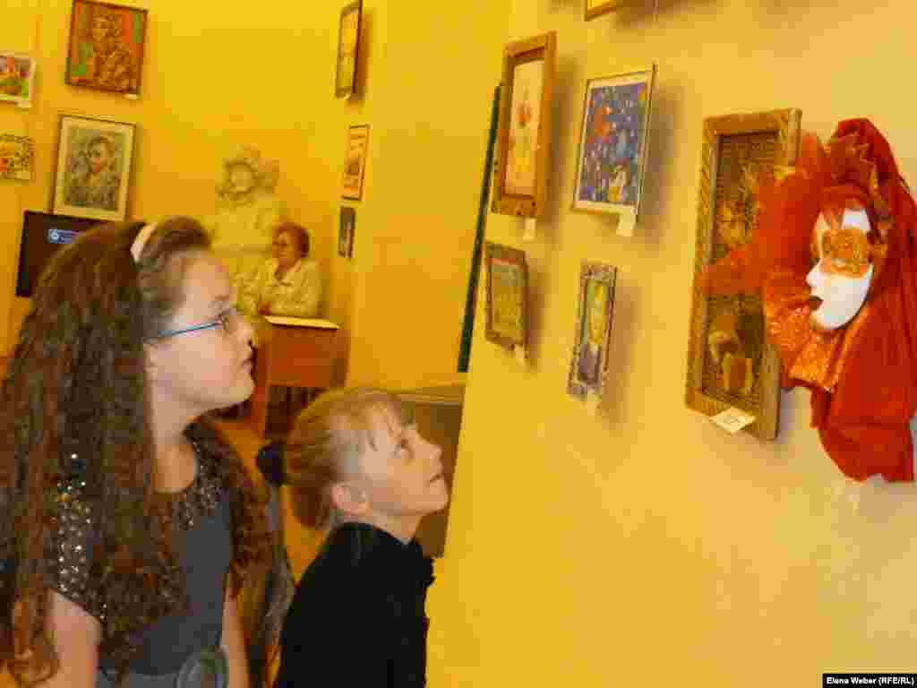 Участницы выставки разглядывают работы других участников.&nbsp;