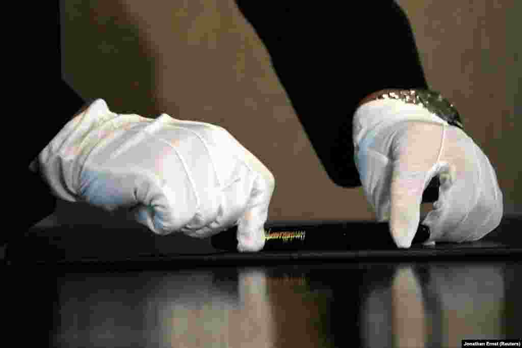 Түндүк Кореянын лидеринин жардамчысы ручканы столго коюп жатат, аны АКШ президенти менен кол коюла турган аземге чейин дыкат сүртүп тазалашкан.&nbsp; &nbsp;