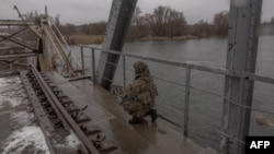 Ukraynalı hərbçi Kupyanskda cəbhə xətti yaxınlığında kəşfiyyat əməliyyatı zamanı Oskol çayı üzərində dağıdılmış dəmiryol körpüsündə dayanır.
