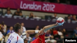 Испанский спортсмен Джон Канеллас (справа) и  сербский спортсмен Момир Илич Сербии (слева) во время матча мужского гандбола на Олимпийских Играх в Лондоне, 29 июля 2012 года. 