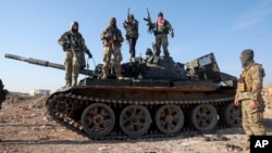 Müxalif döyüşçülər Həma şəhərinin kənarında ələ keçirilən hərbi zirehli maşının üstündə.