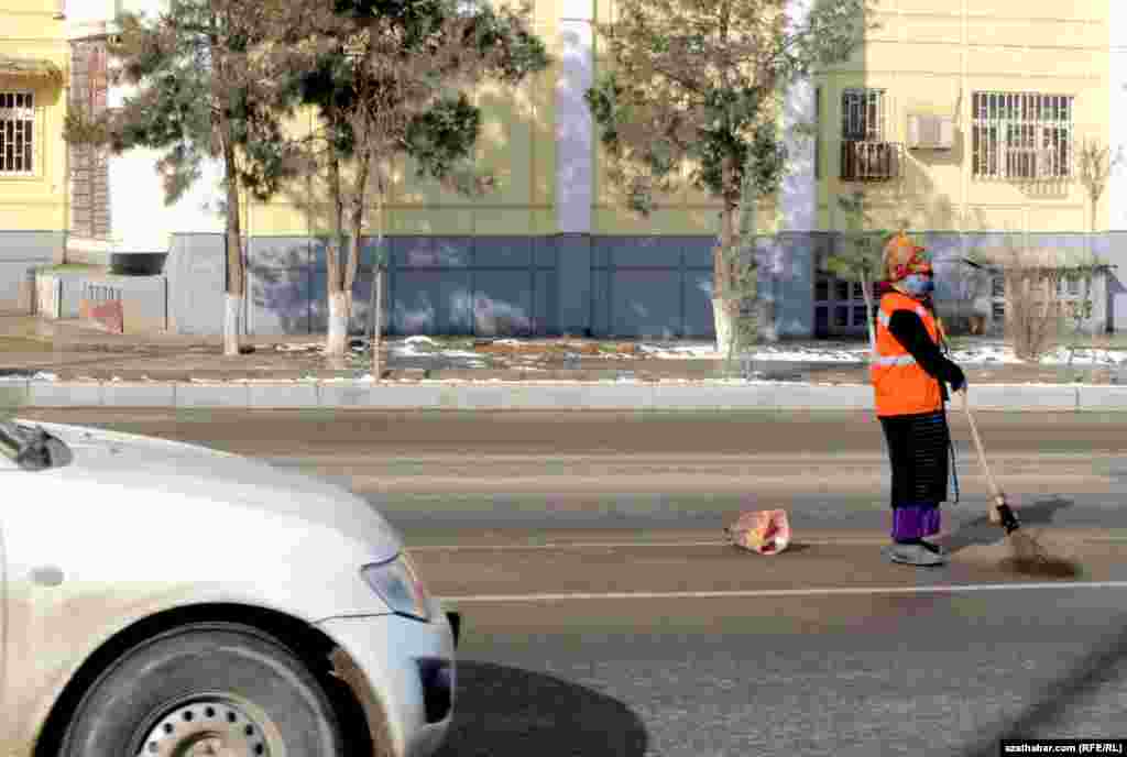 Ýollaryň garyny syryp ýören işçi zenan