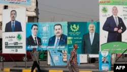 Баш калаа Багдаддын тургундары парламенттик шайлоону утурлай илинген үгүт көрнөктүрүнүн тушунан өтүп баратышат. 6-ноябрь, 2025-жыл.