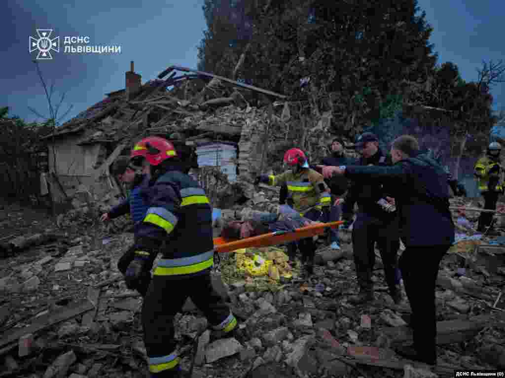 На Львівщині у селі Лапаївка через російську атаку загинула родина з чотирьох людей, зокрема 15-річна дівчинка. Одна людина з родини перебуває у лікарні.На фото: рятувальники несуть пораненого, Лапаївка, Львівська область, 5 жовтня 2025 року