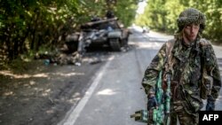 Ukrayna - Rusiyameylli separatçı vurulmuş Ukrayna tankı yanında. 22 iyul 2014