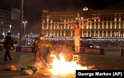 Krisevich poses on a cross with the headquarters of the Federal Security Service (FSB) seen in the background during a protest in Moscow late last year.