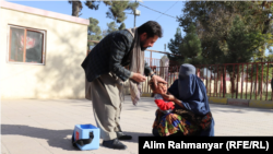 یک خانم در جوزجان کودکش را برای گرفتن واکسین پولیو به یکی از مراکز صحی آورده است.