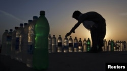 Пакистандык бала таң азандан суу сатканга камданууда. Карачи, Клифтон жээги. 15-март, 2012