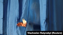 UKRAINE -- A woman walks out of a voting booth at a polling station during the second round of a presidential election in Kyiv, Ukraine April 21, 2019