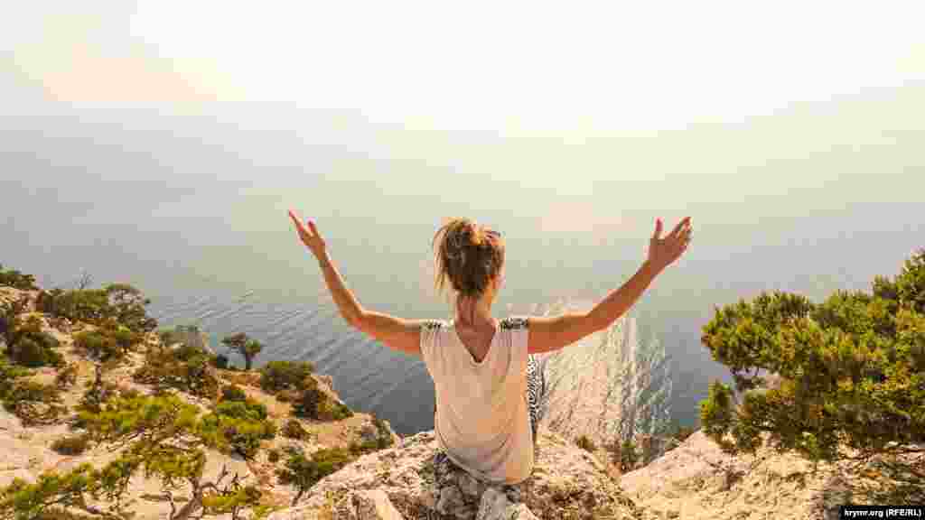 Жінка сидить на валуні гори Караул-Оба