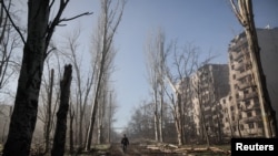 یکی از ساکنان در نزدیکی ساختمان‌های آپارتمانی آسیب‌دیده از حملۀ نظامی روسیه در شهر کوستیانتینیفکا، واقع در خط مقدم، قدم می‌زند.