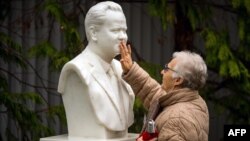 A woman touches a bust of the late Yugoslav and Serbian President Slobodan Milosevic at his grave in the town of Pozarevac.