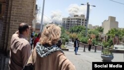 Тегерандын тургундары талкаланган имараттарды карап турат. 