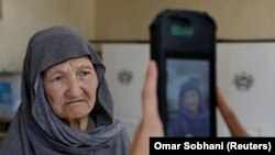 کارمند کمیسیون انتخابات در یکی از مراکز رایگیری در کابل با دستگاه بیومتریک عکس یک رأی دهنده را می‌گیرد. 28, 2019.REUTERS