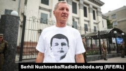 Ğayıp olğan Ervin İbragimovnıñ babası Umer İbragimov Kyivdeki Rusiye elçihanesiniñ binası ögünde oğluna qol tutuv aktsiyasında. 2018 senesi iyülniñ 24-ü