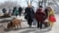 Мужчина с собакой вместе с другими жителями Мариуполя направляется к месту эвакуации из осажденного российскими войсками города, 20 марта 2022 года